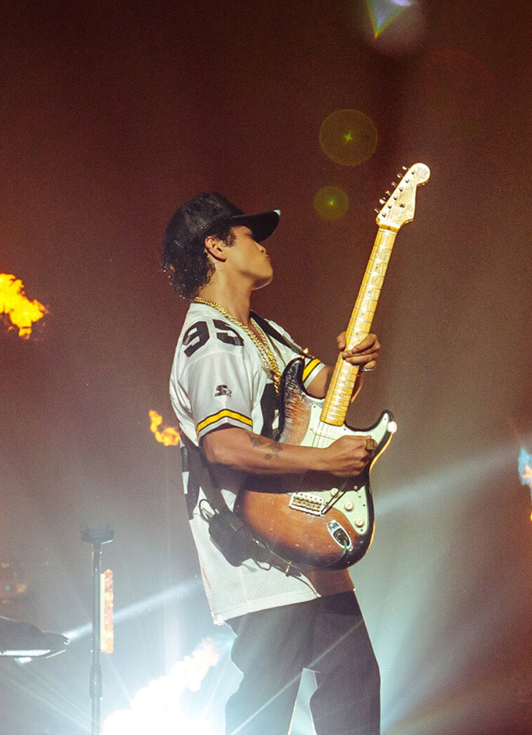 Bruno Mars plays a guitar surrounded by flames onstage at the Cisco Showcase.