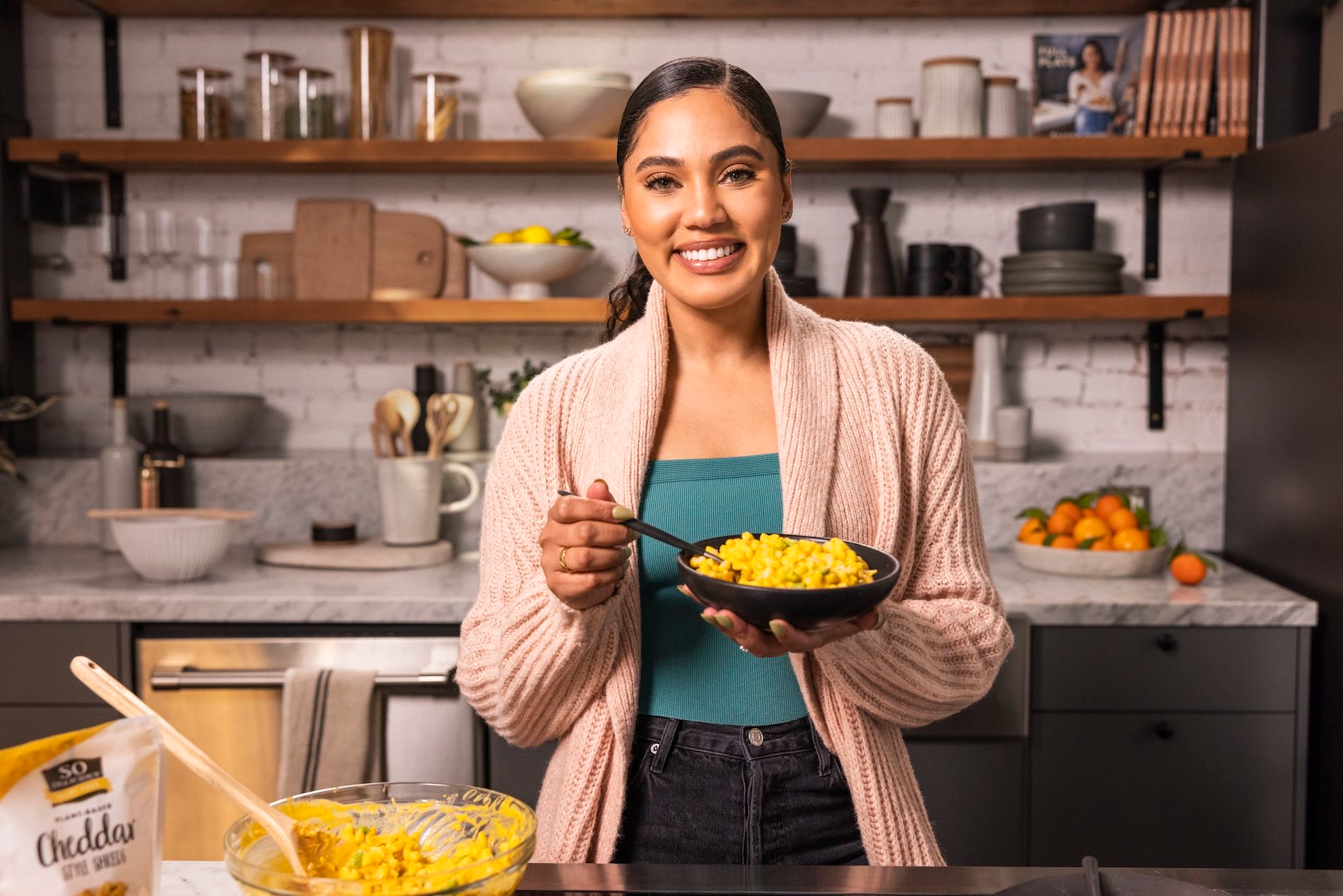 Ayesha Curry poses with a bowl of plant-based mac-and-cheese for So Delicious.