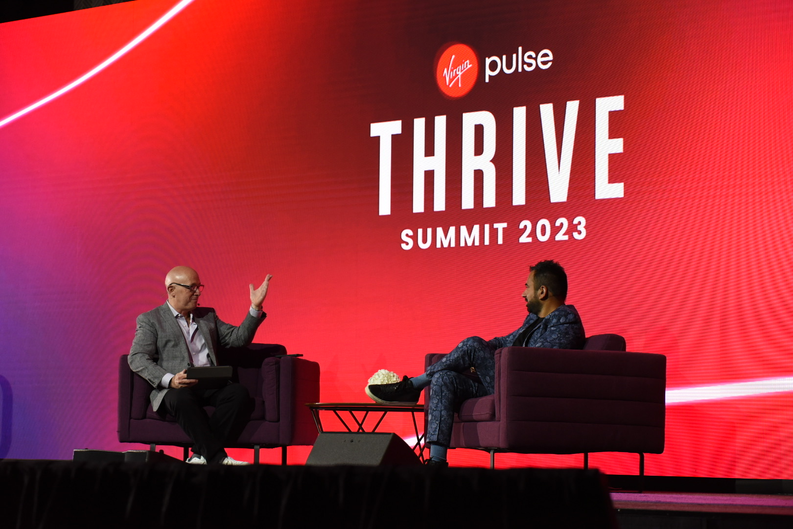 A man and Kal Penn speak onstage at the Virgin Pulse 2023 Summit.