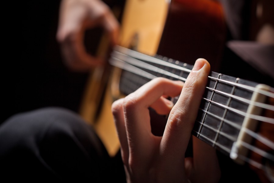 A close-up of a guitarist playing a barre chord.