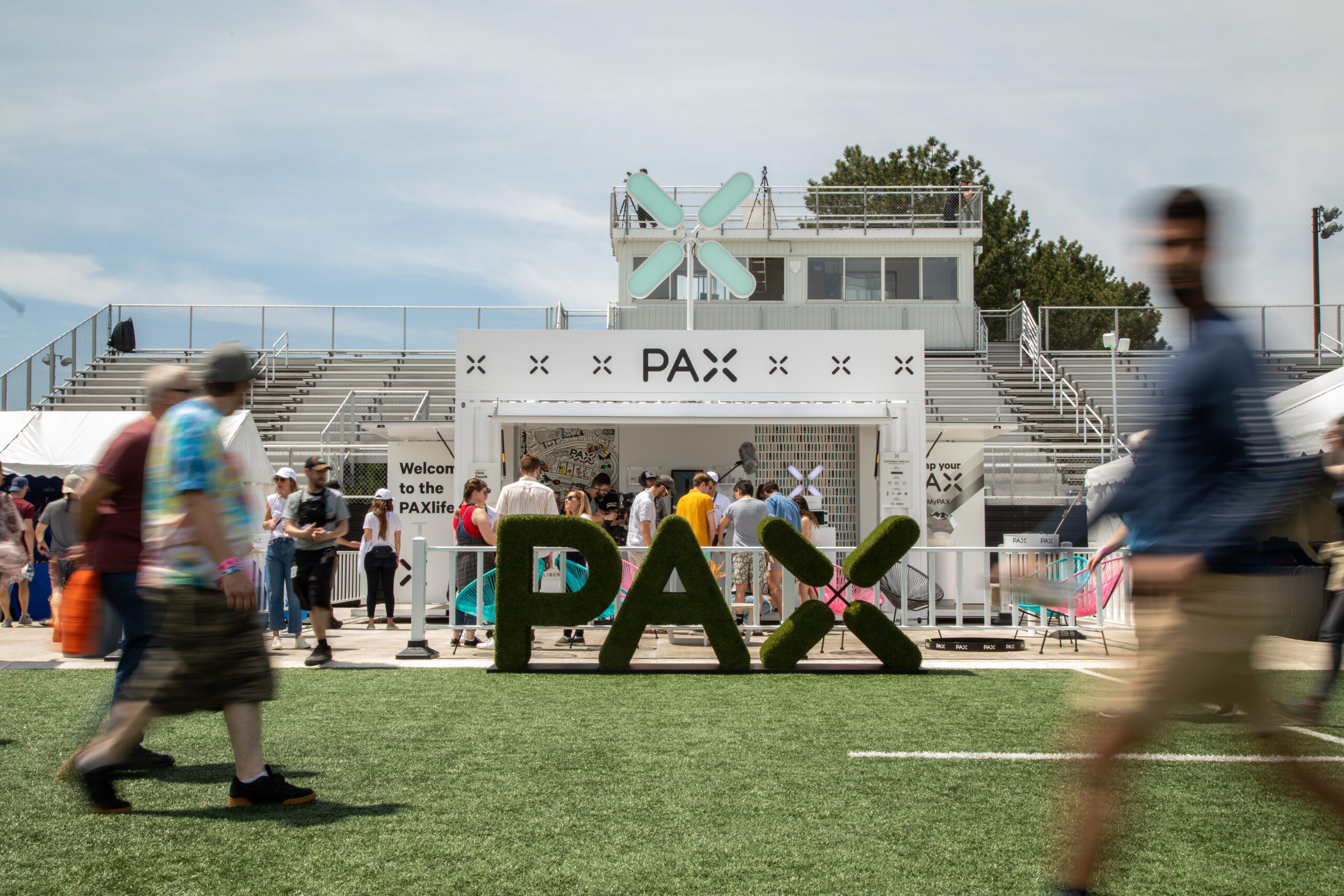 Guests walk on the grass at the PAX Lab experiential brand activation as part of their festival tour
