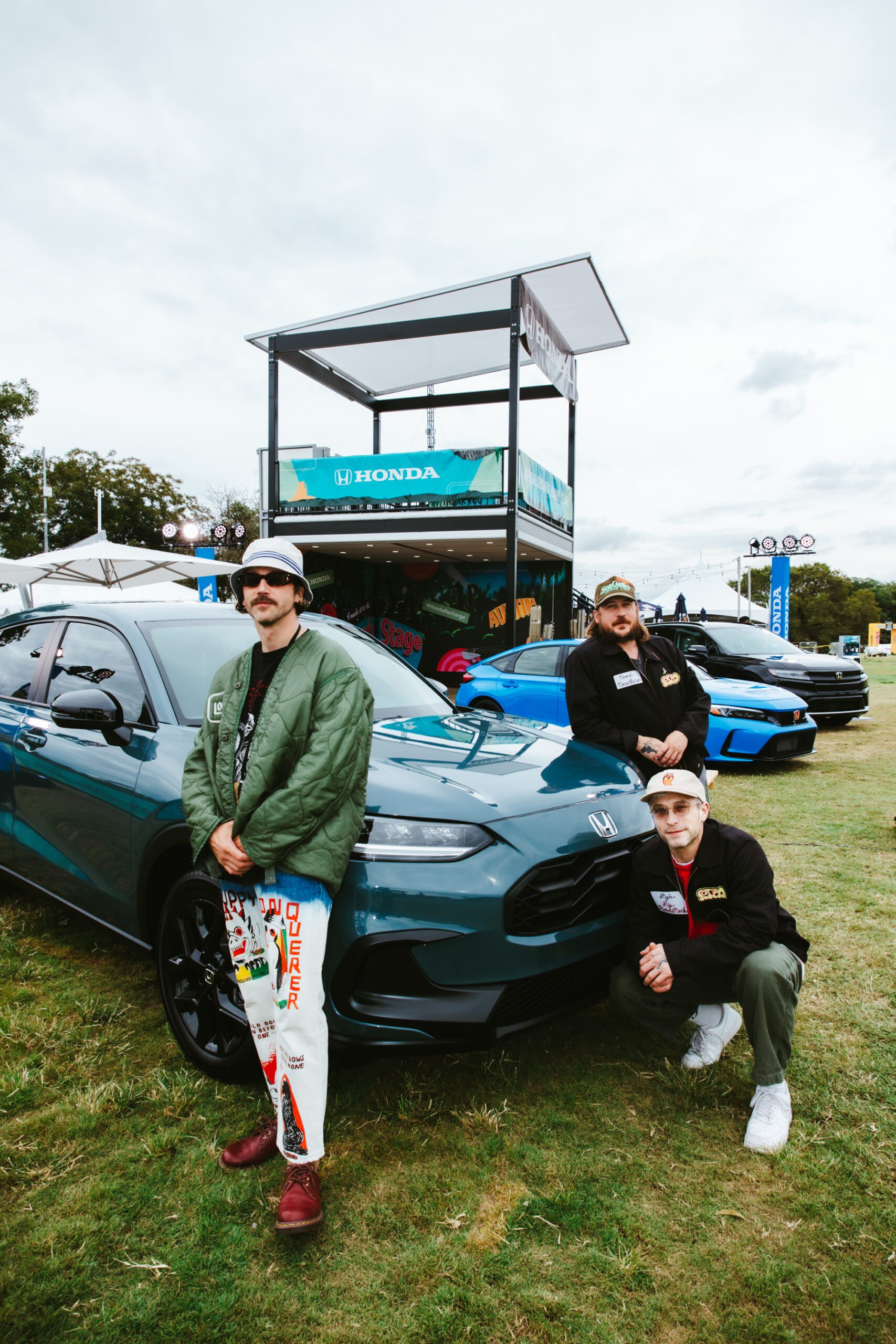 Three pose by a green Honda.