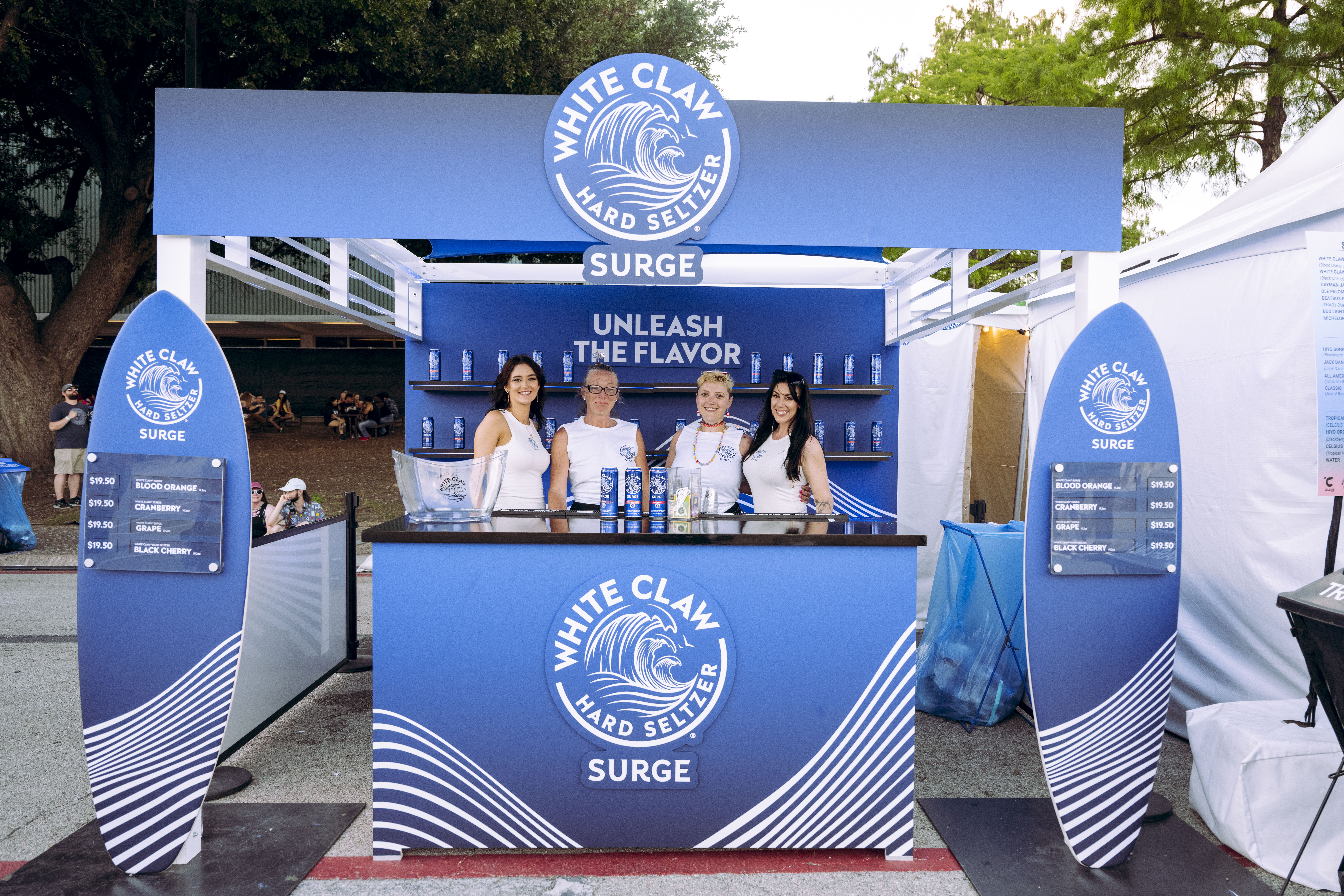 White Claw Surge 10x10 bar at Breakaway Music Festival with bartenders posing in front of a wall of product